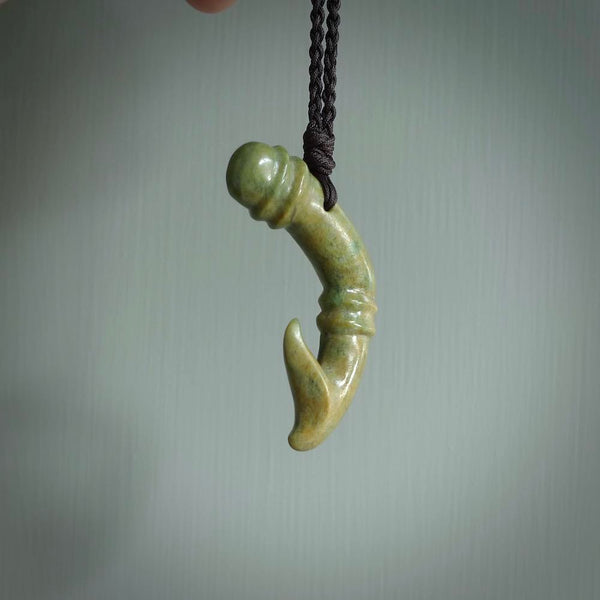 This photo shows a beautiful flower jade bamboo hook suspended from a hand plaited brown cord. The bamboo hook was carved for us by Jen Hung who is a master jade carver from New Zealand.