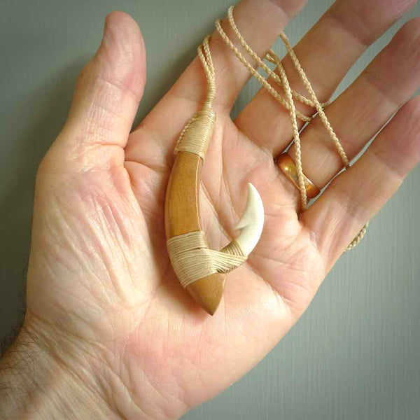 This picture shows a large matau, hook called a pā kahawai. It is carved from bone,  wood, and paua shell. One only, free shipping worldwide. Provided with an adjustable beige cord. Stunning work of Art to Wear by Andrew Doughty.