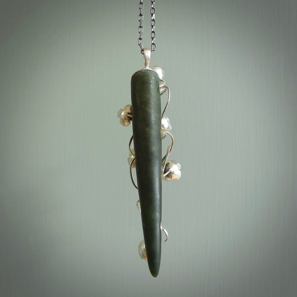 This picture shows a beautiful jade drop pendant with sterling silver flowers. This is a spectacular work of art and is a one off piece. Hand carved from New Zealand Jade with sterling silver flowers, replicating flowers in a vase.