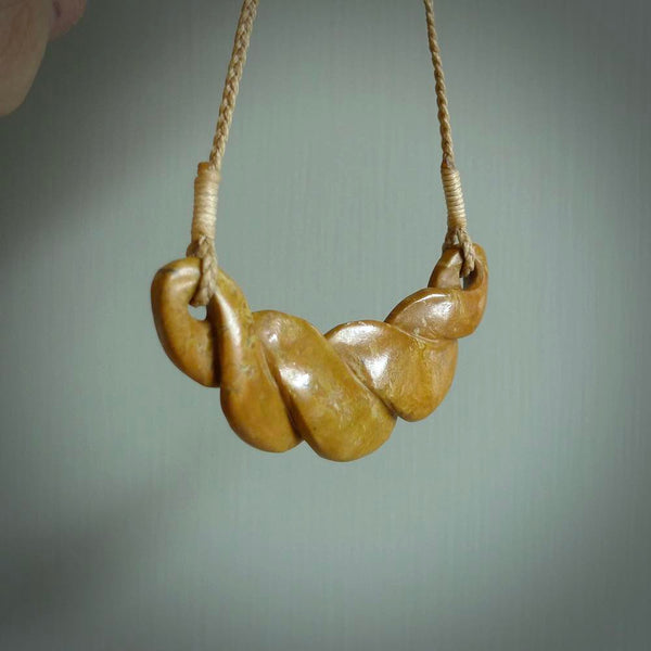 This piece is a large, contemporary, twist pendant. It was carved for us by Alex Sands from a lovely orange piece of New Zealand Flower jade. It is suspended on a tan coloured braided cord that is length adjustable.