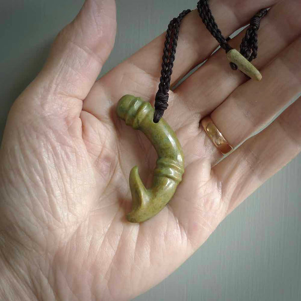 This photo shows a beautiful flower jade bamboo hook suspended from a hand plaited brown cord. The bamboo hook was carved for us by Jen Hung who is a master jade carver from New Zealand.