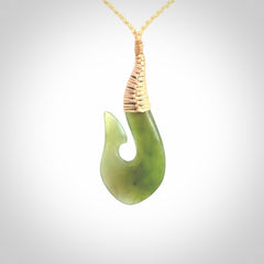 This picture shows a green jade hook pendant, also called a hei-matau, carved for us in New Zealand jade. The carver is Ric Moor - and this is a beautiful example of his work. The cord is a four-plait, adjustable fine beige coloured necklace.