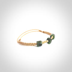 Hand carved New Zealand jade adjustable bracelet with beige cord. Carved in New Zealand jade by Ric Moor for NZ Pacific. One only armband for women and men.