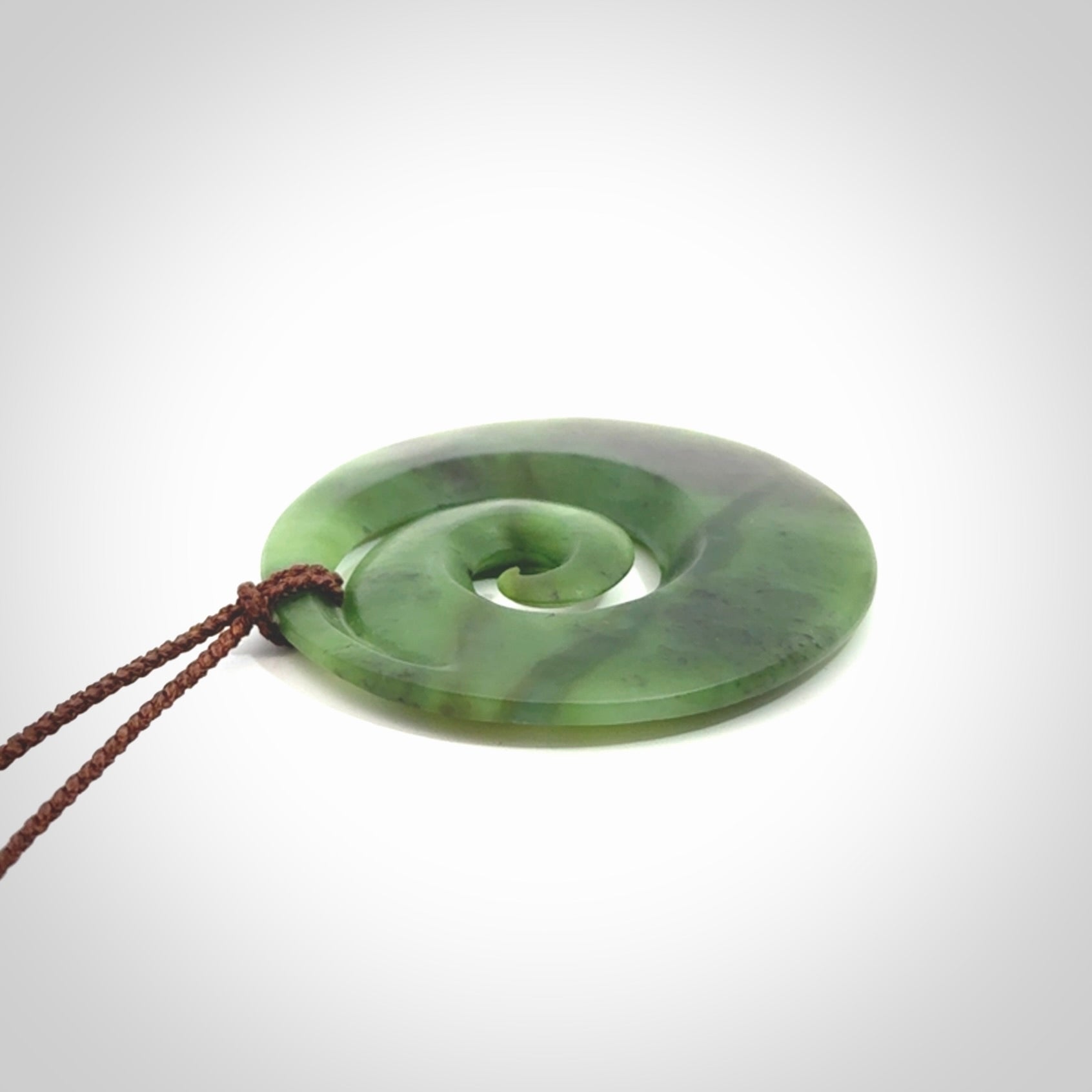 This picture shows a hand carved New Zealand jade koru pendant