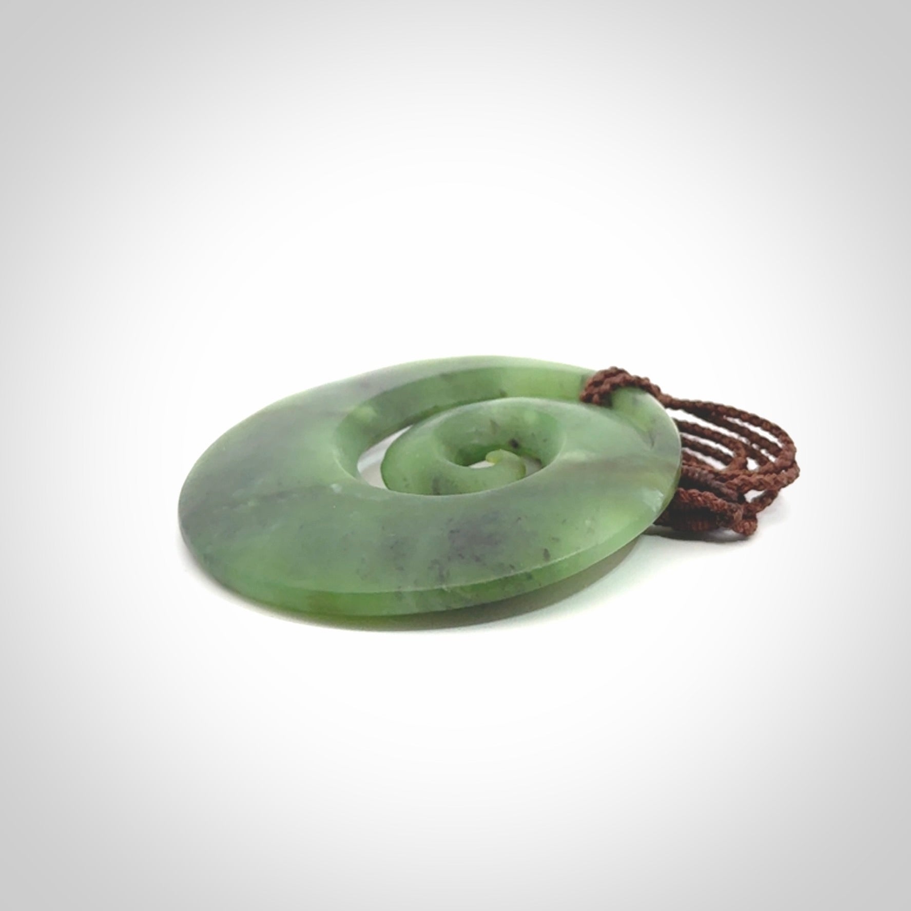 This picture shows a hand carved New Zealand jade koru pendant