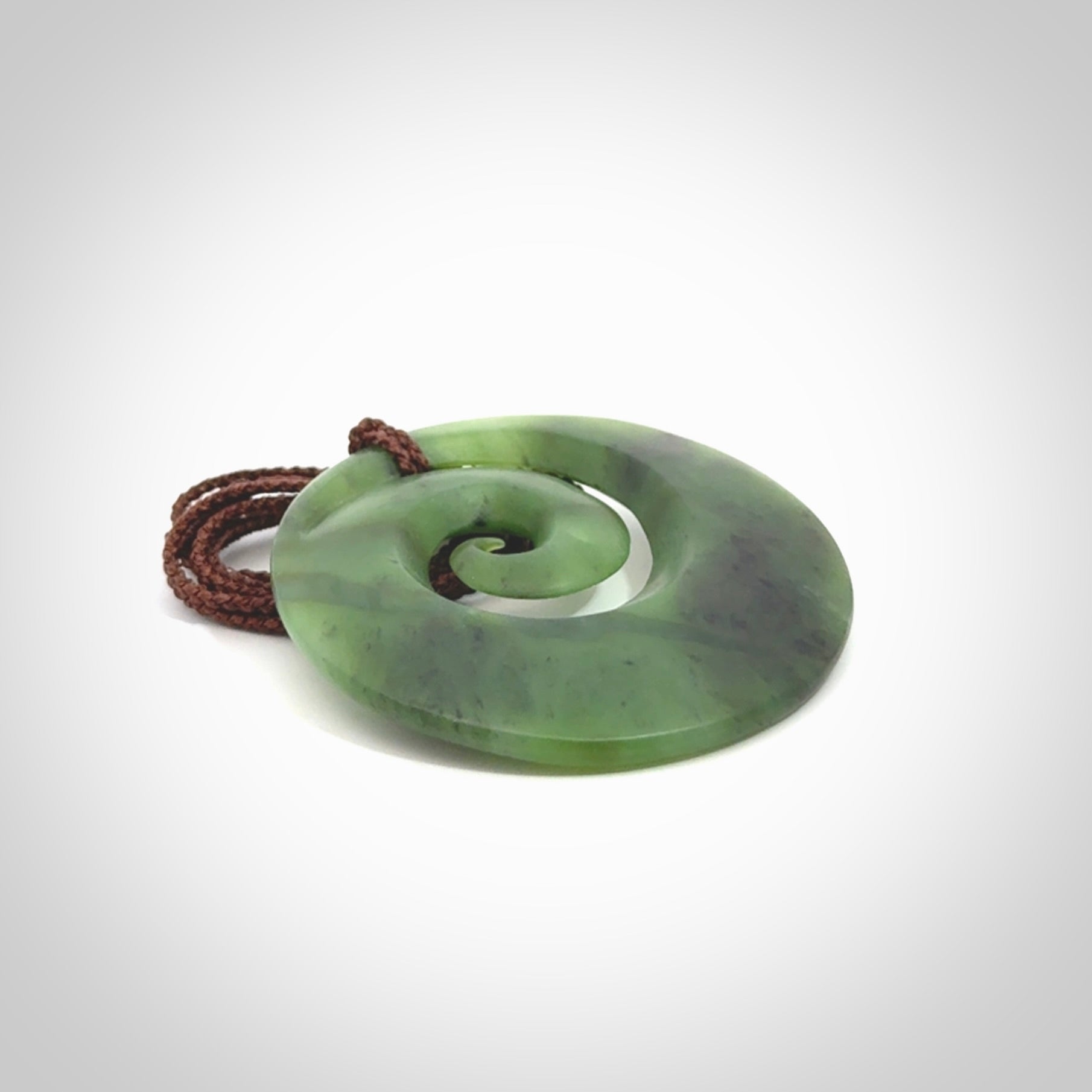 This picture shows a hand carved New Zealand jade koru pendant