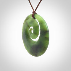 This picture shows a hand carved New Zealand jade koru pendant
