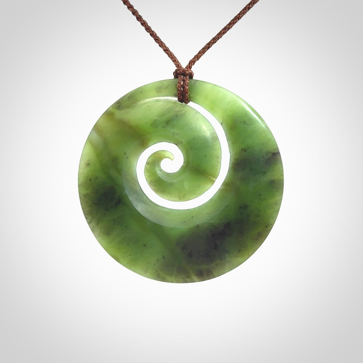 This picture shows a hand carved New Zealand jade koru pendant
