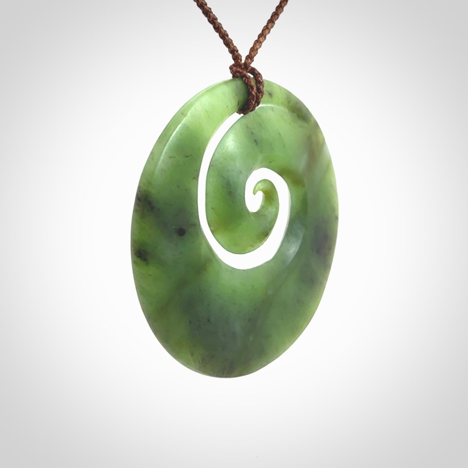This picture shows a hand carved New Zealand jade koru pendant