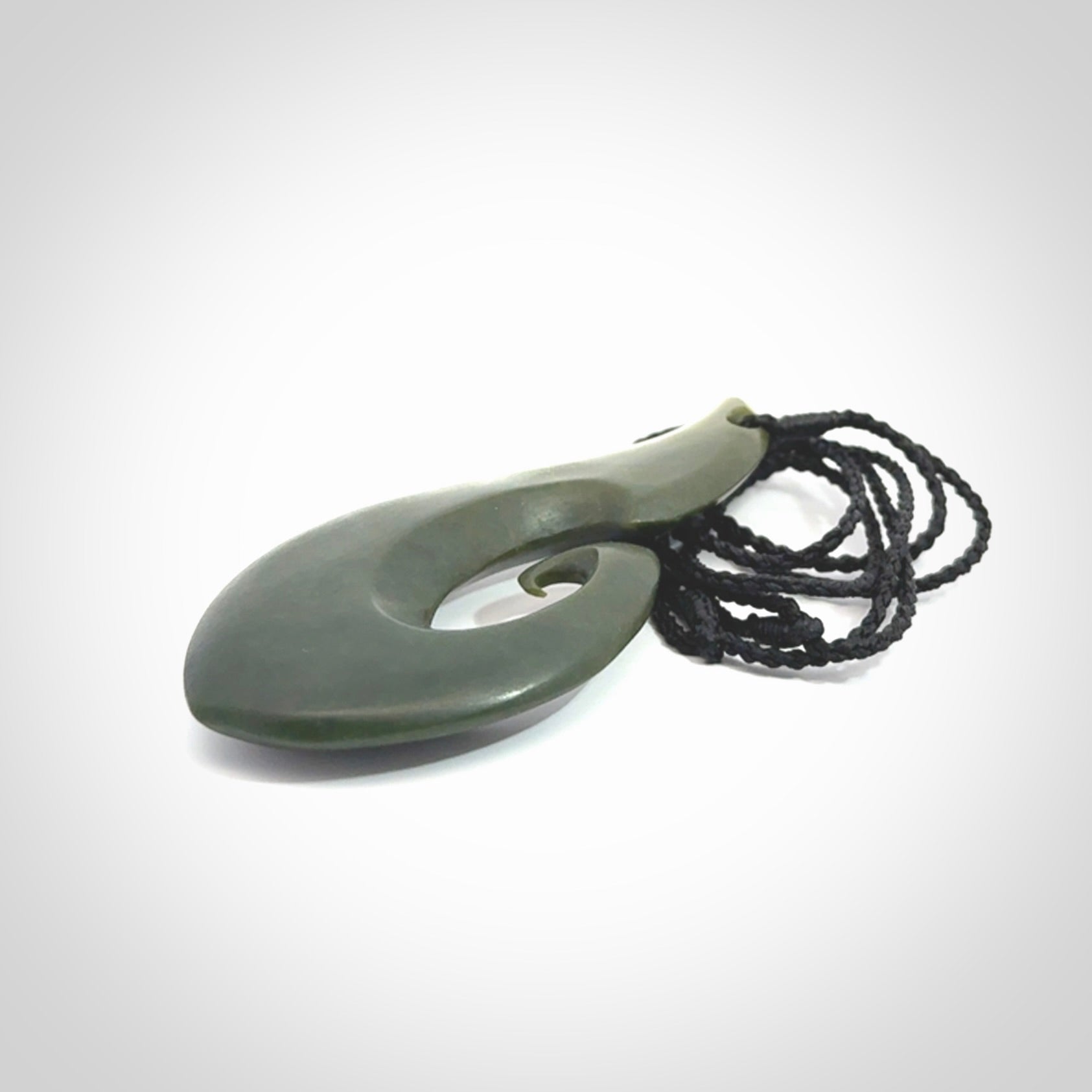 This picture shows a hand carved jade koru pendant. It is a deep green colour and is a wonderful, large sized piece of jewellery. The cord is a four plait black colour and adjustable so that you can position the pendant where it suits you best. This koru was carved for us by Ric Moor. Delivery is free worldwide.