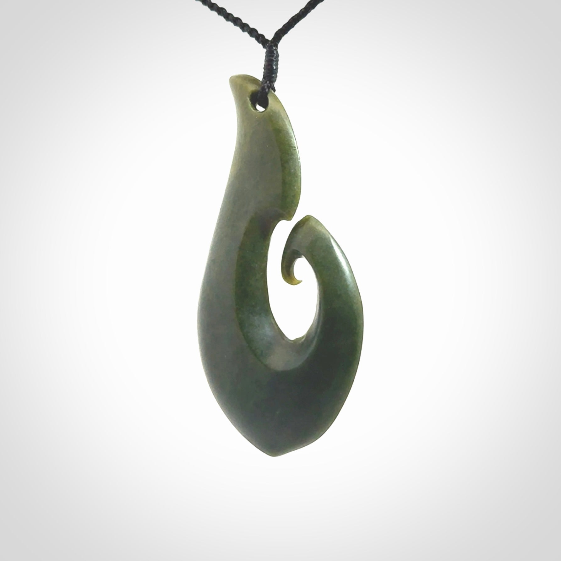This picture shows a hand carved jade koru pendant. It is a deep green colour and is a wonderful, large sized piece of jewellery. The cord is a four plait black colour and adjustable so that you can position the pendant where it suits you best. This koru was carved for us by Ric Moor. Delivery is free worldwide.