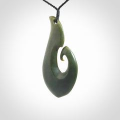 This picture shows a hand carved jade koru pendant. It is a deep green colour and is a wonderful, large sized piece of jewellery. The cord is a four plait black colour and adjustable so that you can position the pendant where it suits you best. This koru was carved for us by Ric Moor. Delivery is free worldwide.