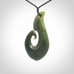 This picture shows a hand carved jade koru pendant. It is a deep green colour and is a wonderful, large sized piece of jewellery. The cord is a four plait black colour and adjustable so that you can position the pendant where it suits you best. This koru was carved for us by Ric Moor. Delivery is free worldwide.