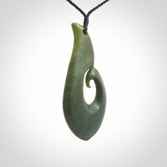 This picture shows a hand carved jade koru pendant. It is a deep green colour and is a wonderful, large sized piece of jewellery. The cord is a four plait black colour and adjustable so that you can position the pendant where it suits you best. This koru was carved for us by Ric Moor. Delivery is free worldwide.