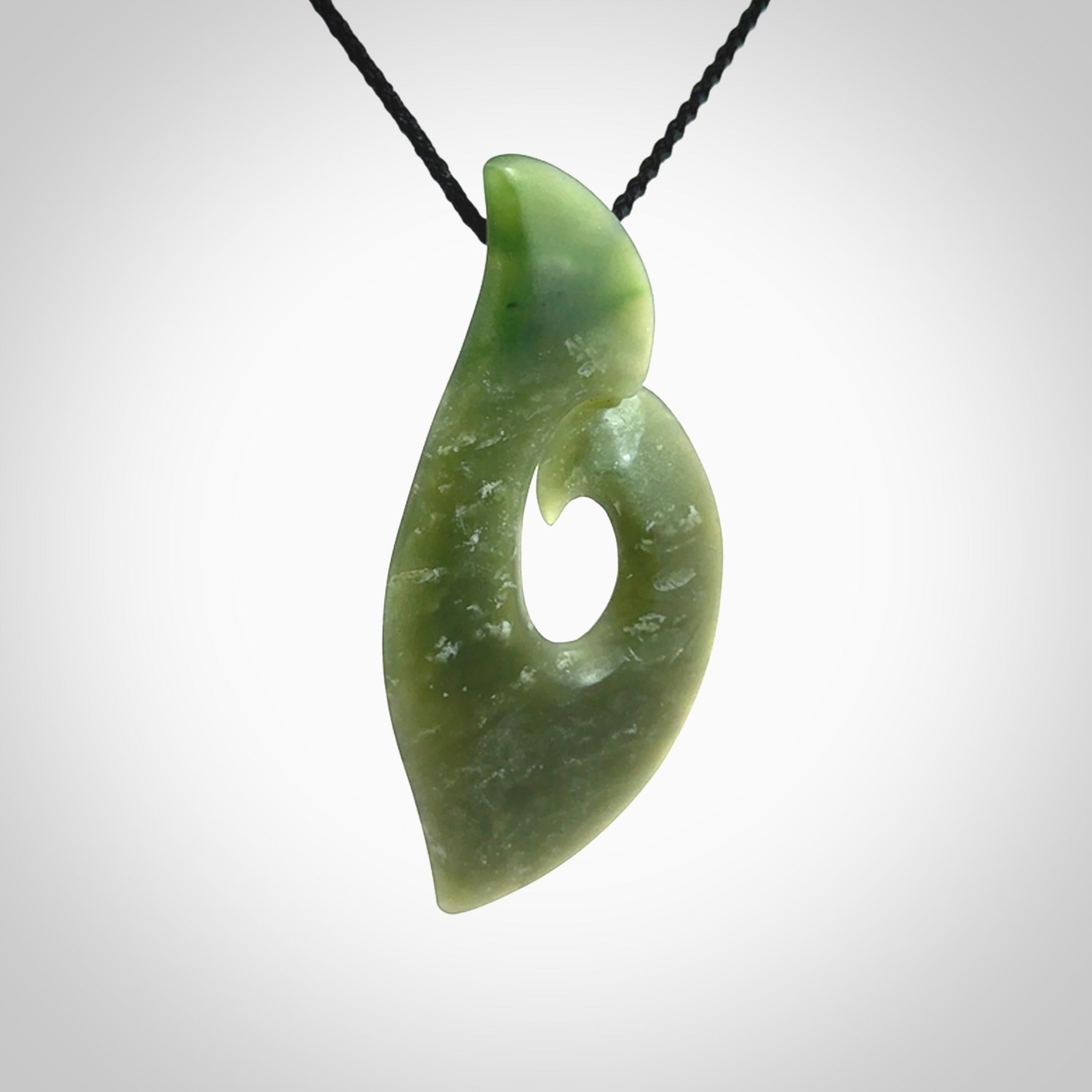 This picture shows a hand carved jade koru pendant. It is a deep green colour and is a wonderful, piece of jewellery. The cord is a four plait black colour and adjustable so that you can position the pendant where it suits you best. Delivery is free worldwide.