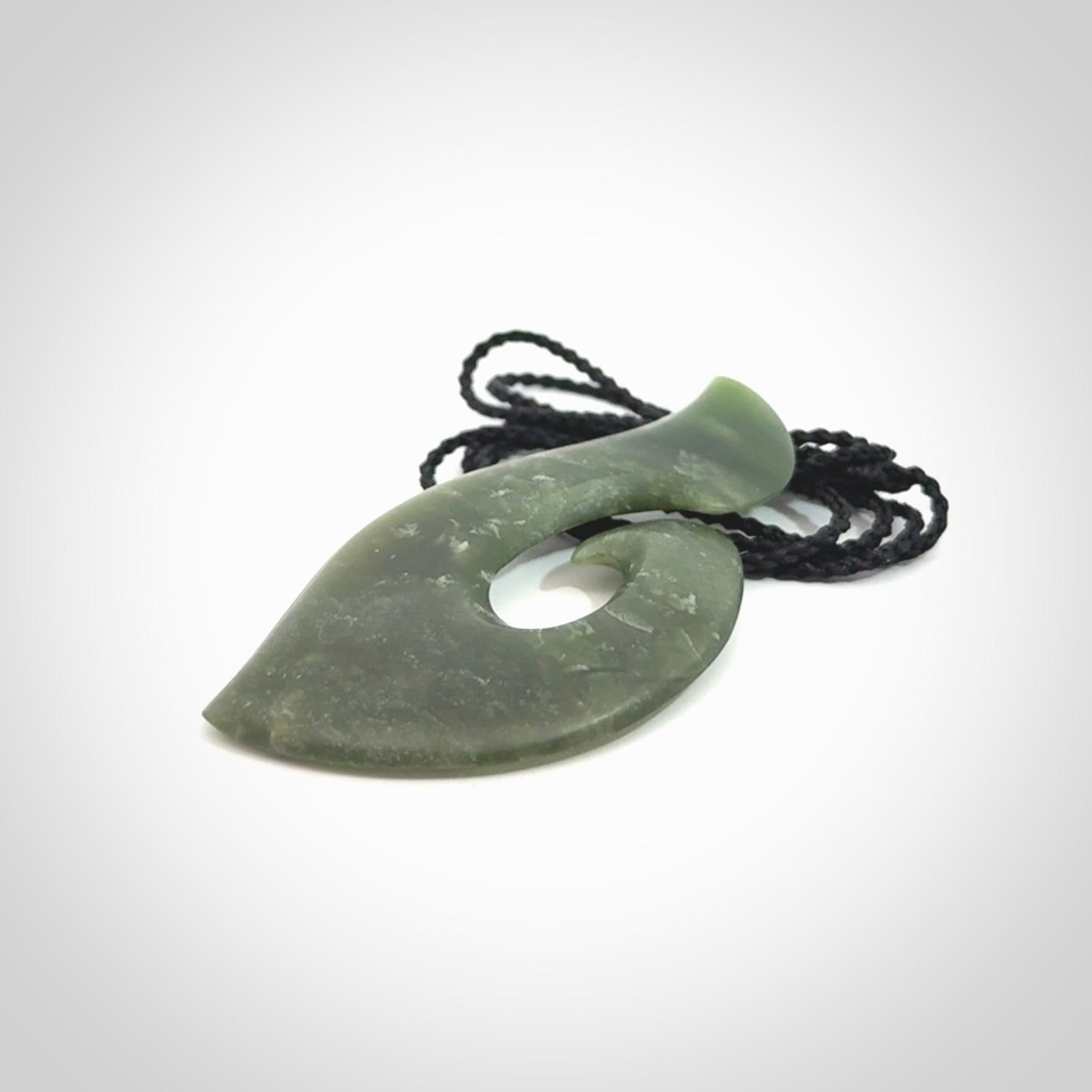 This picture shows a hand carved jade koru pendant. It is a deep green colour and is a wonderful, piece of jewellery. The cord is a four plait black colour and adjustable so that you can position the pendant where it suits you best. Delivery is free worldwide.
