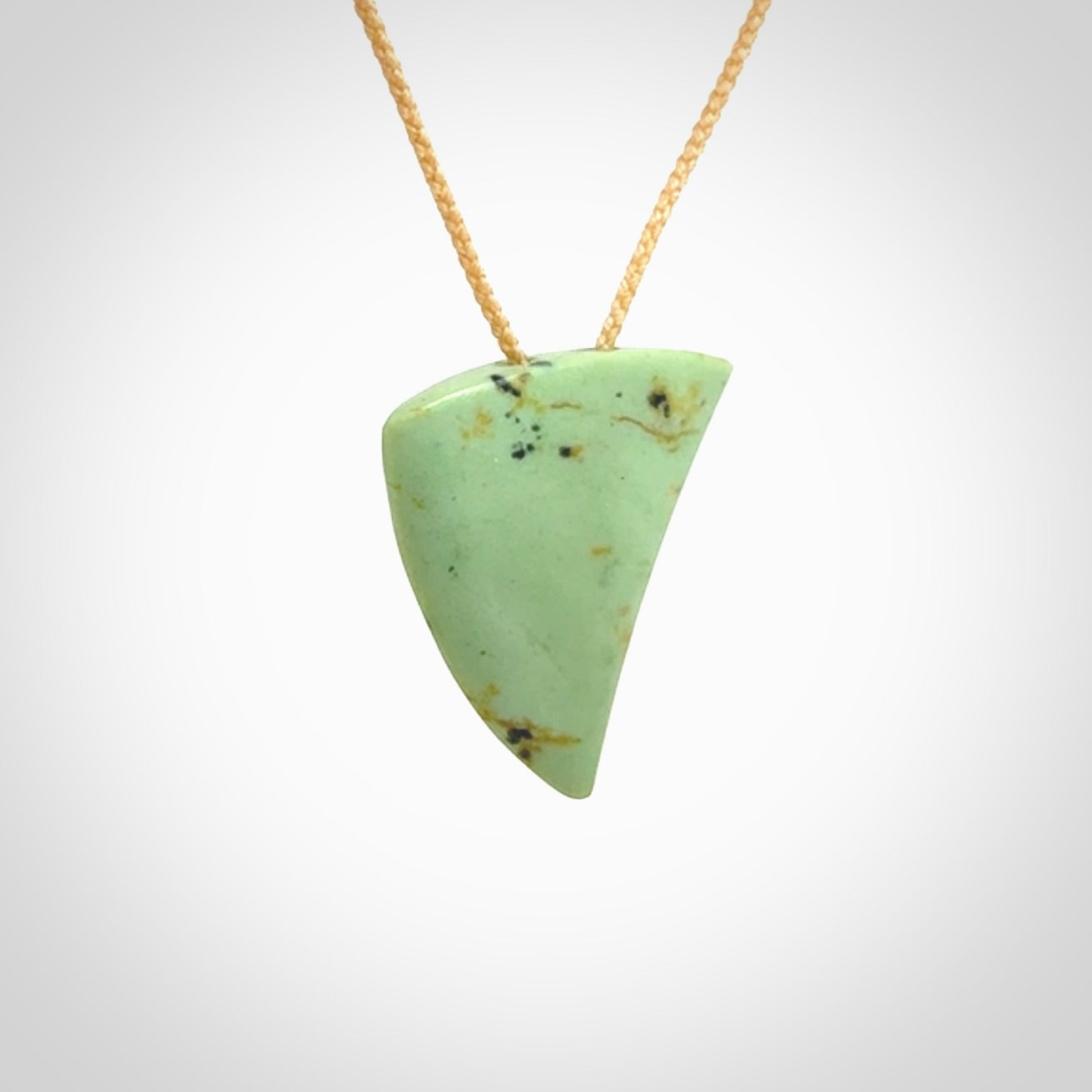 This is a lovely New Zealand Jade, pounamu niho drop pendant. It is bound with an adjustable beige coloured cord which is length adjustable.