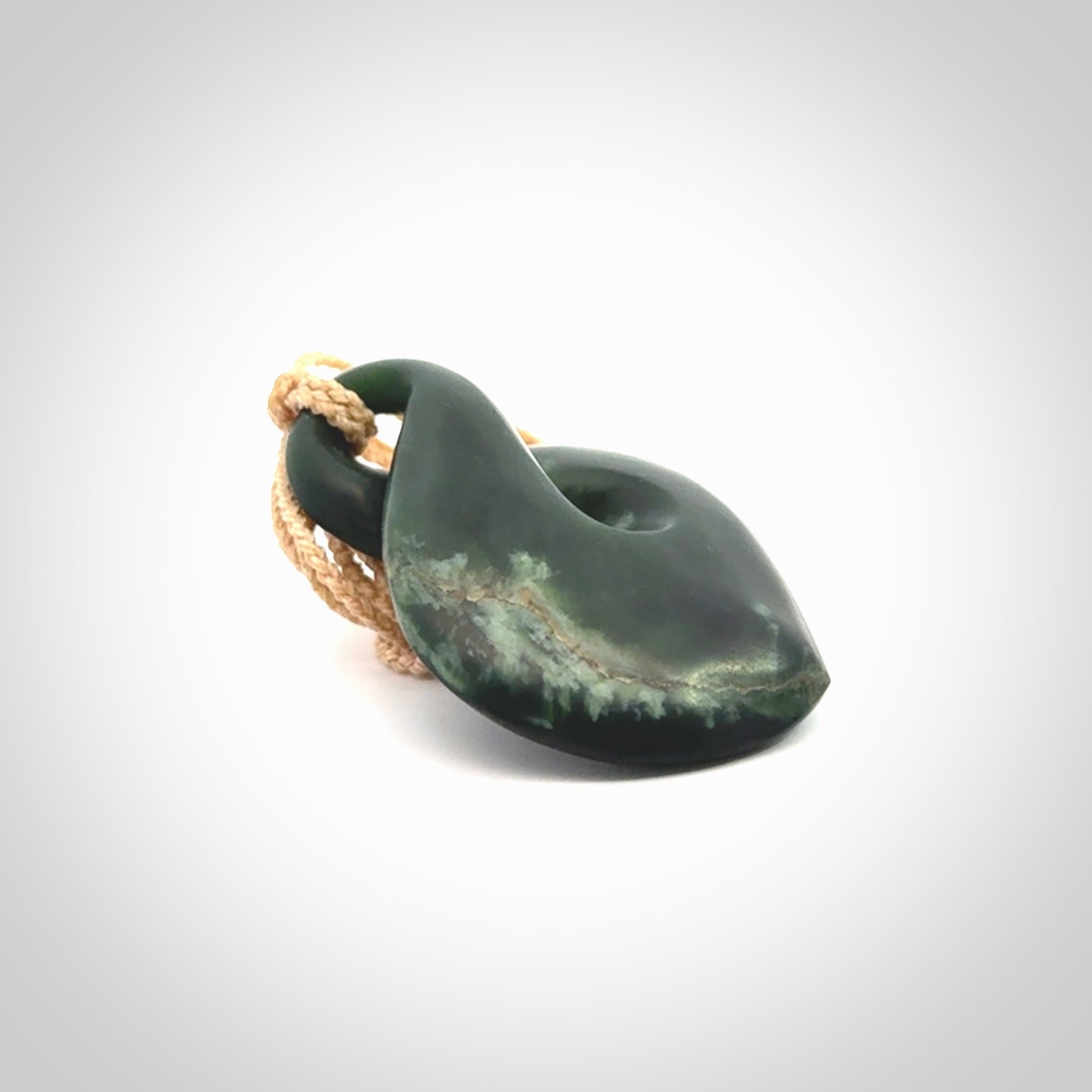 This piece is a drop shaped, single twist pendant. It was carved for us by Ric Moor from a lovely deep green piece of New Zealand jade. It is suspended on an beige four plaited braided cord that is length adjustable.