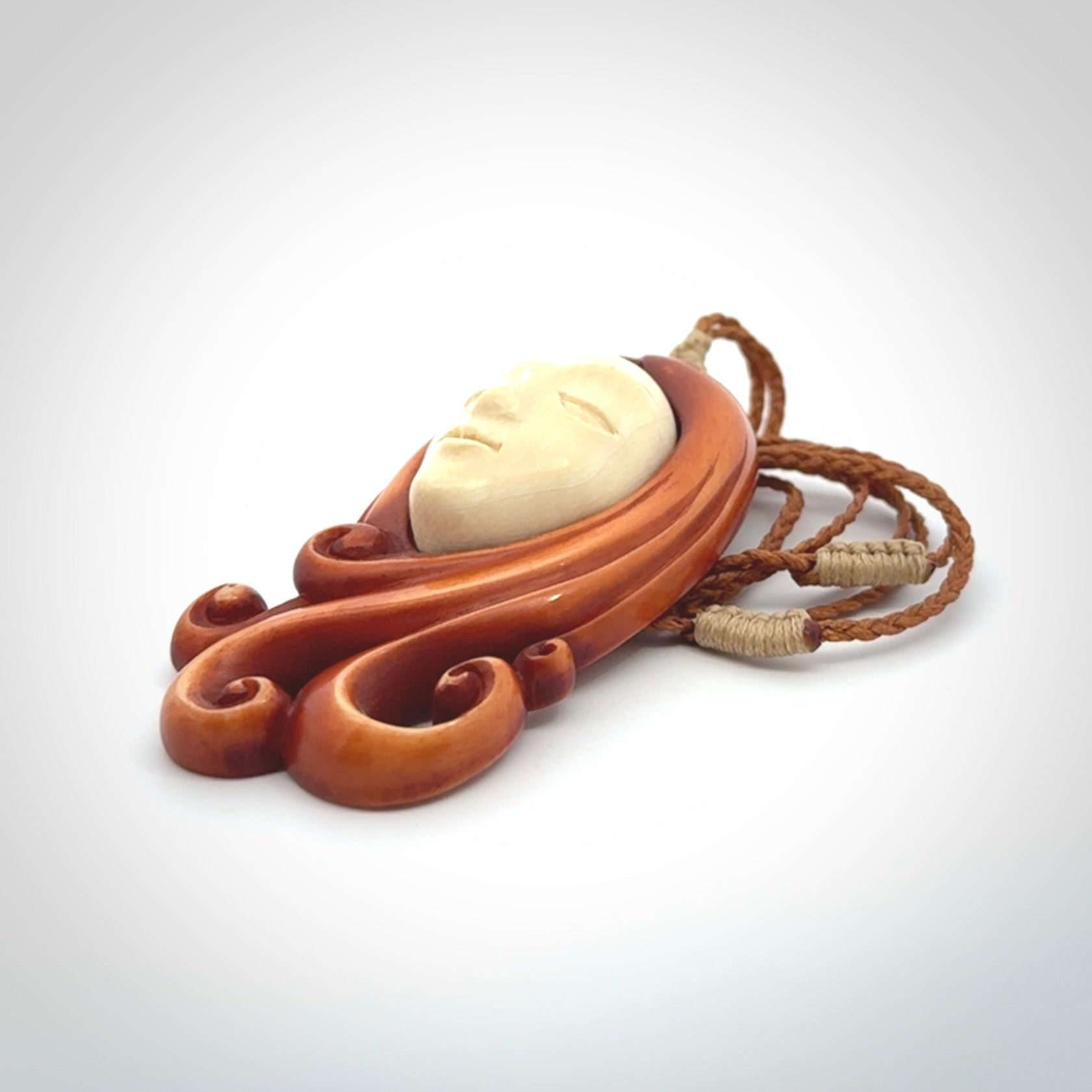 This is a hand carved bone contemporary female pendant. Yuri Terenyi has carved this from Stained Bone with Woolly Mammoth Tusk and Paua Shell inlay on the back of the pendant. It is a delightful, large and artistic piece of jewellery. One only necklace. The necklace is provided on an adjustable cord in a hand made, custom, wooden box.