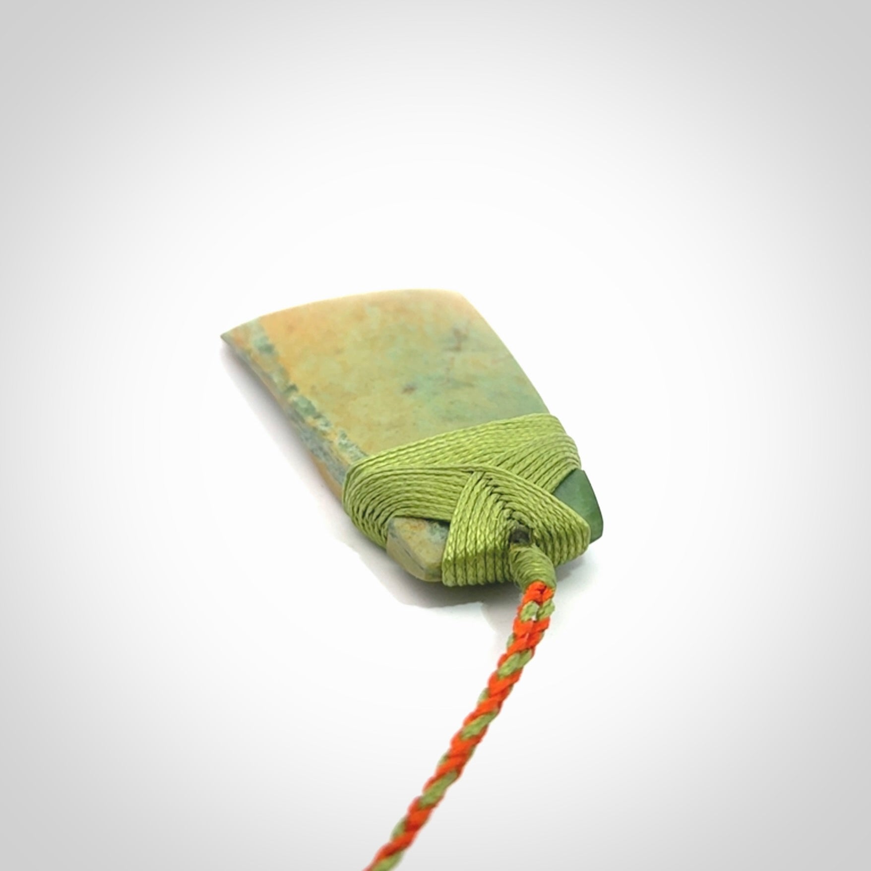 Hand carved Toki pendant from a lovely piece of local New Zealand Flower Jade. We have suspended this from a orange and green cord which can be adjusted with a couple of slip knots and green binding.