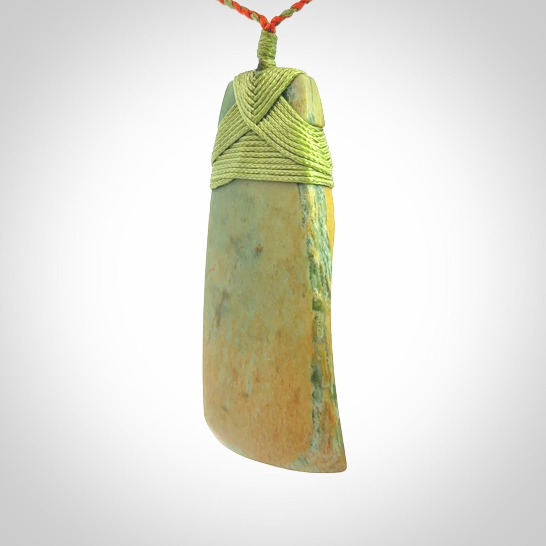 Hand carved Toki pendant from a lovely piece of local New Zealand Flower Jade. We have suspended this from a orange and green cord which can be adjusted with a couple of slip knots and green binding.