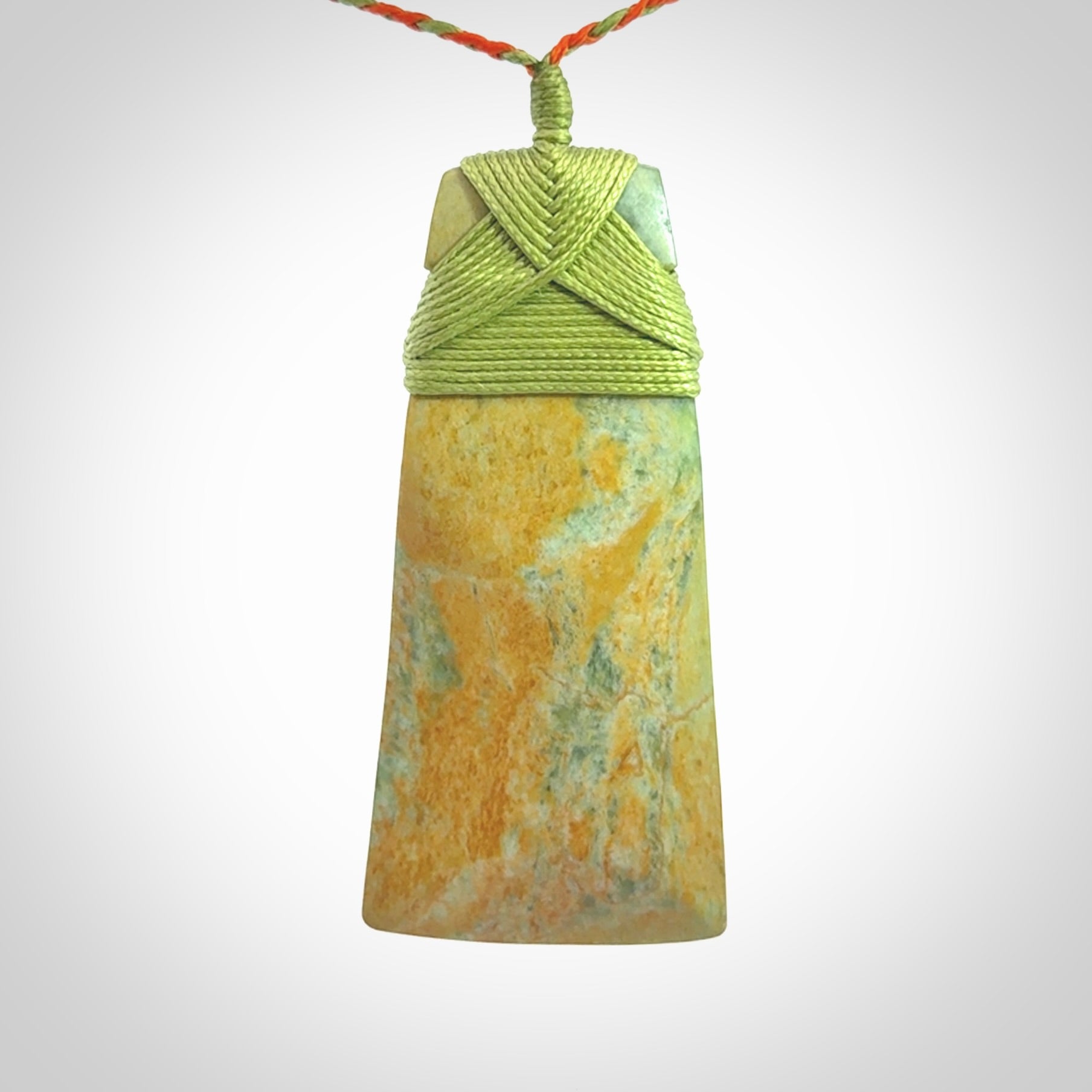 Hand carved Toki pendant from a lovely piece of local New Zealand Flower Jade. We have suspended this from a orange and green cord which can be adjusted with a couple of slip knots and green binding.