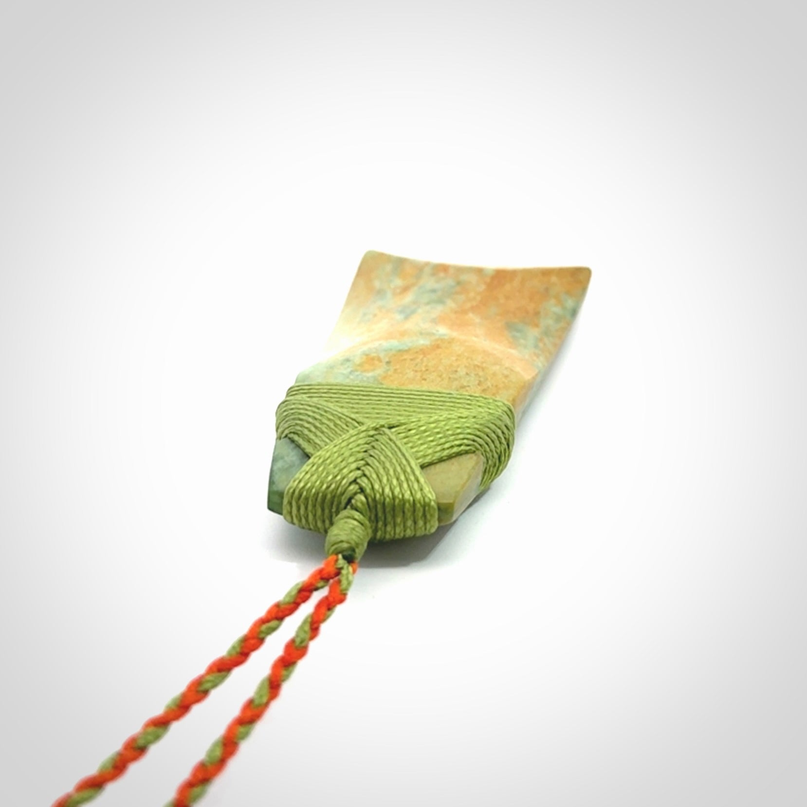 Hand carved Toki pendant from a lovely piece of local New Zealand Flower Jade. We have suspended this from a orange and green cord which can be adjusted with a couple of slip knots and green binding.