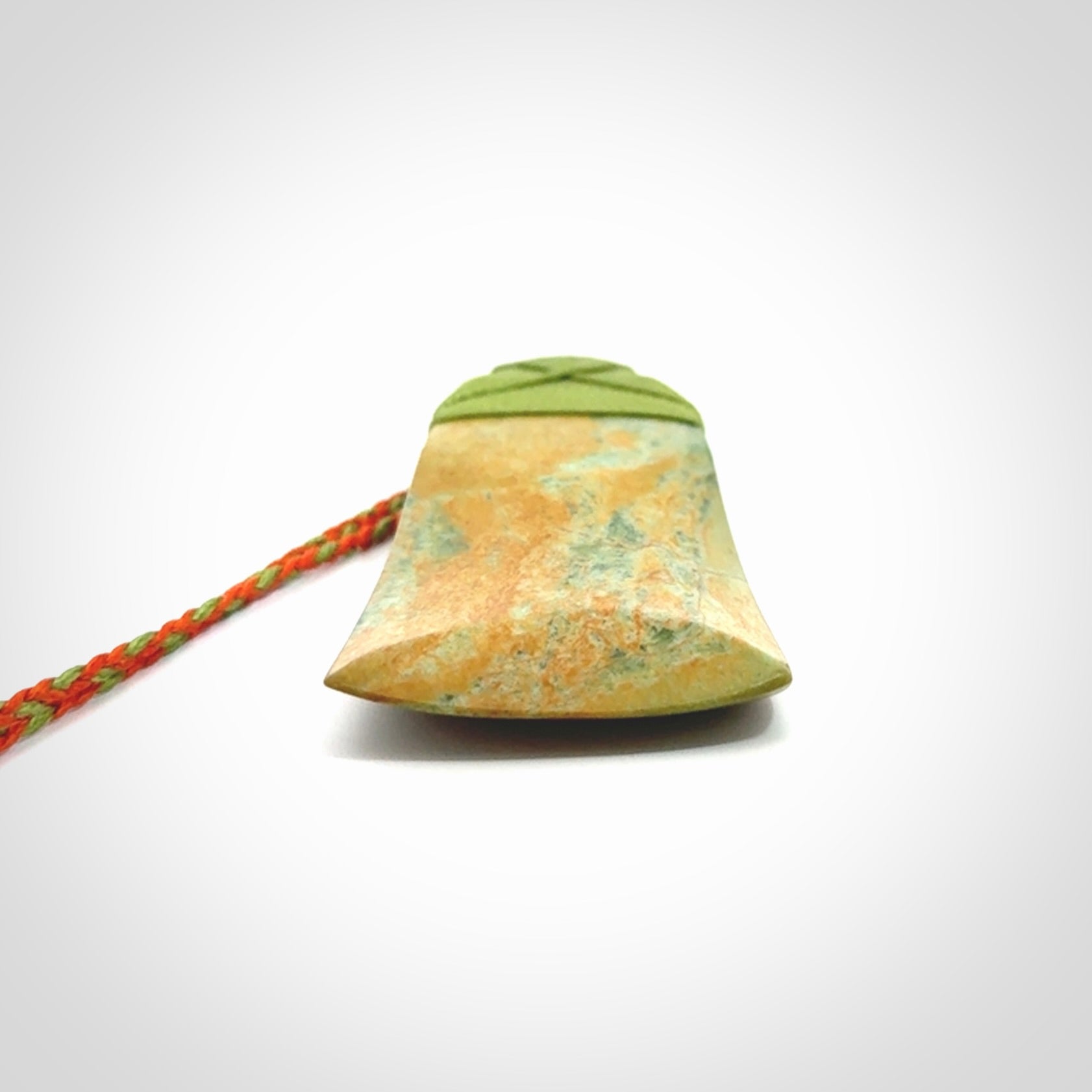 Hand carved Toki pendant from a lovely piece of local New Zealand Flower Jade. We have suspended this from a orange and green cord which can be adjusted with a couple of slip knots and green binding.