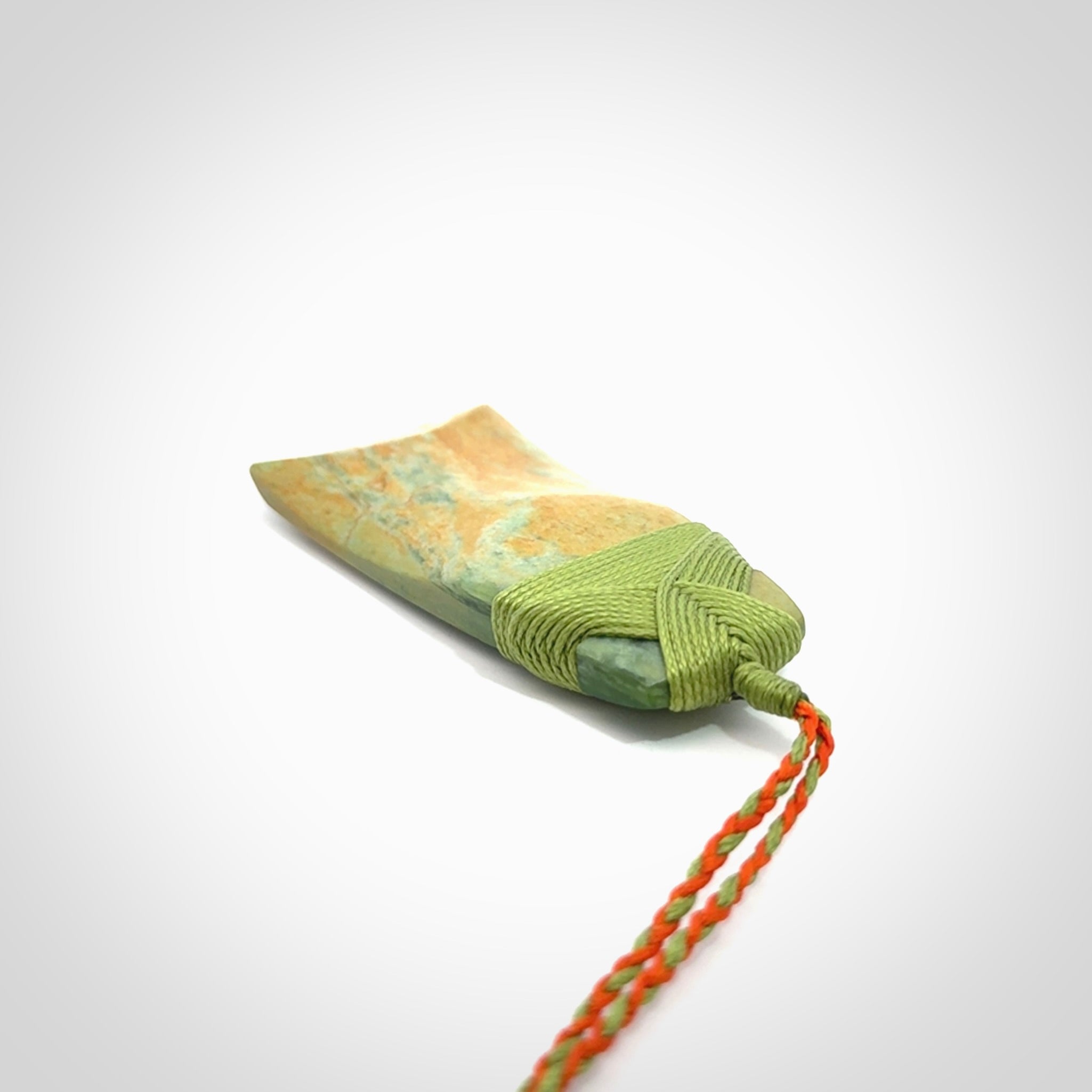 Hand carved Toki pendant from a lovely piece of local New Zealand Flower Jade. We have suspended this from a orange and green cord which can be adjusted with a couple of slip knots and green binding.
