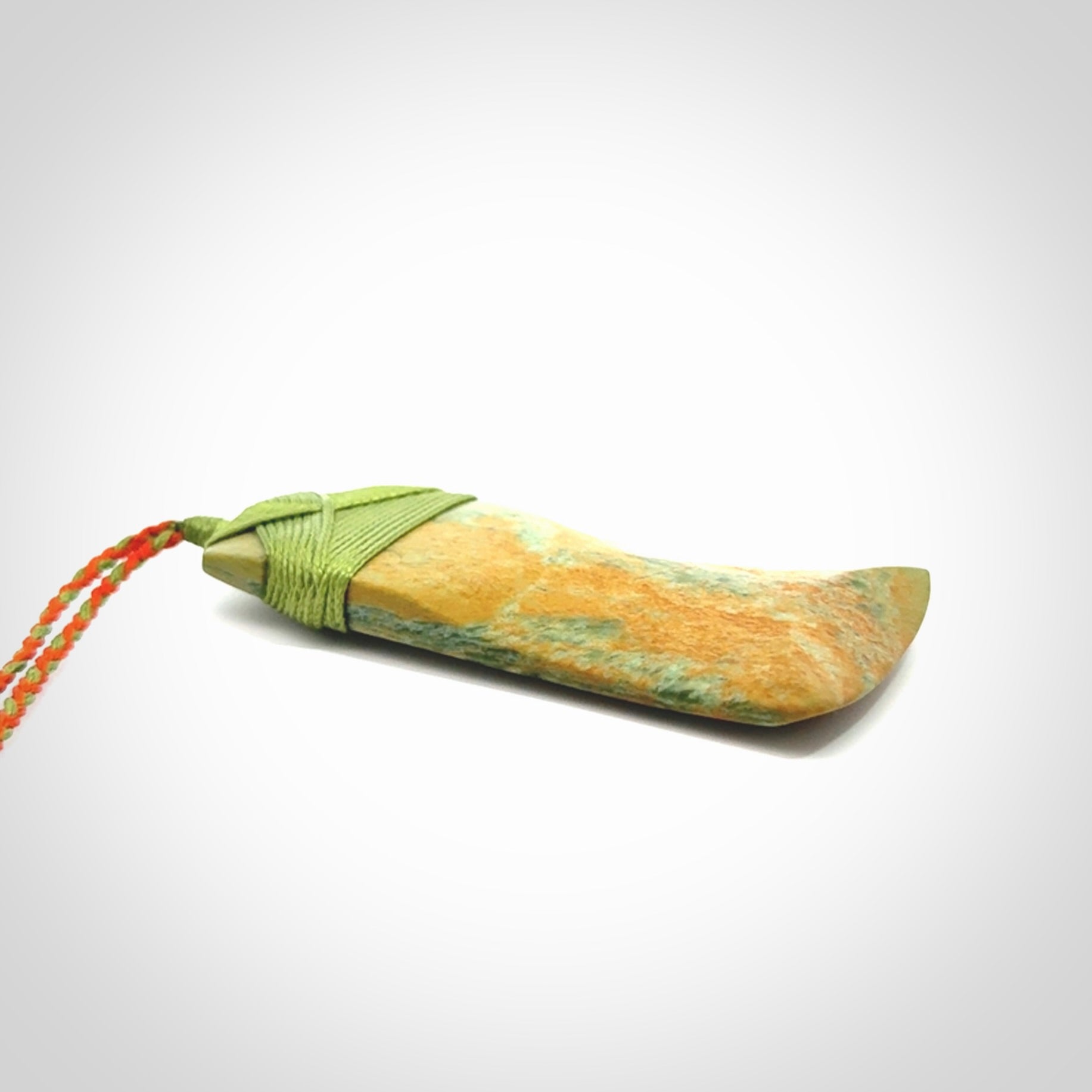 Hand carved Toki pendant from a lovely piece of local New Zealand Flower Jade. We have suspended this from a orange and green cord which can be adjusted with a couple of slip knots and green binding.