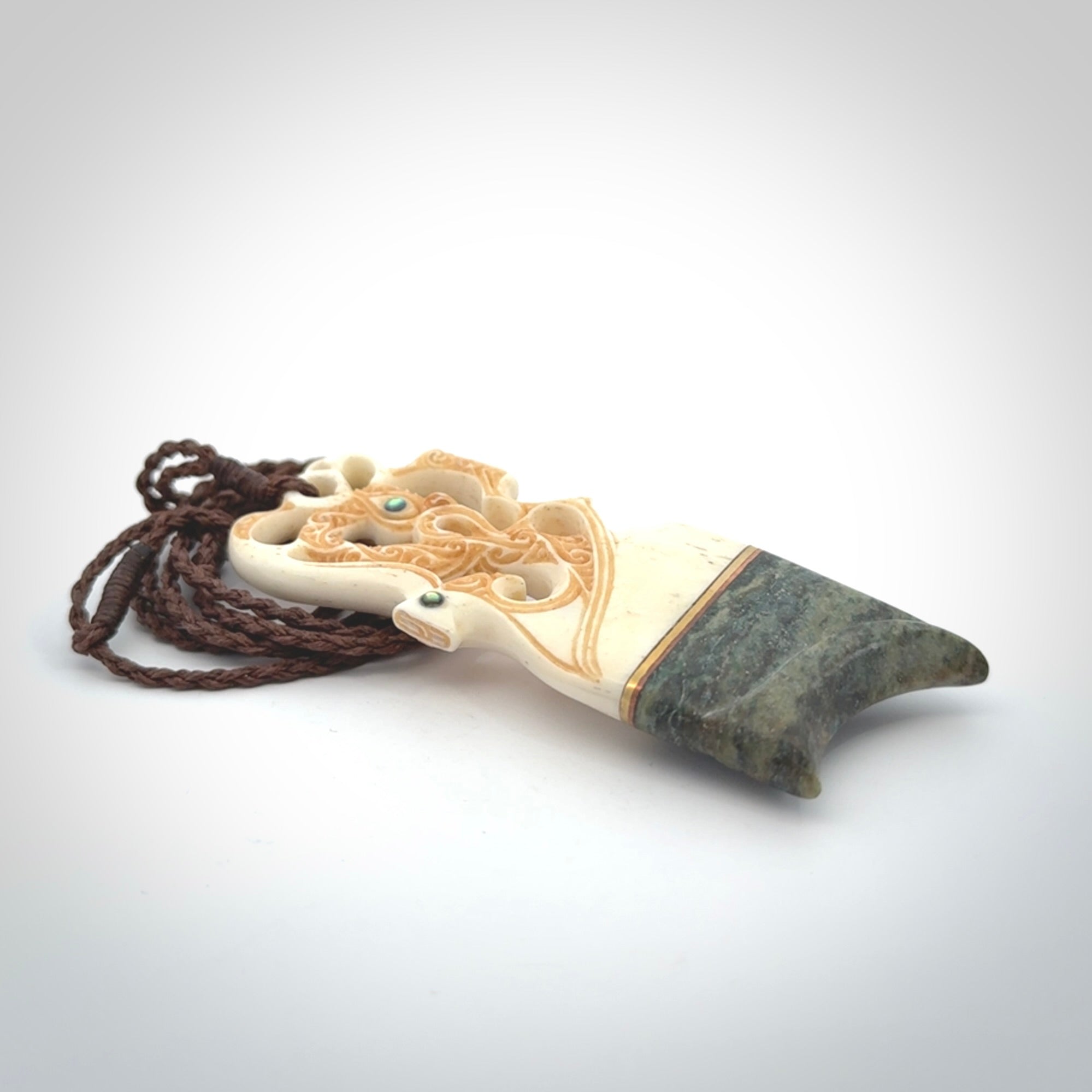 This is a large carved Manaia pendant. It is made from unique materials - New Zealand Obay Stone, Bone, Paua shell, Brass. The face of the Manaia is carved with a traditional design in the front. It is carved front and back and has traditional carved designs. This is a large and very traditional pendant that is a collectors piece.