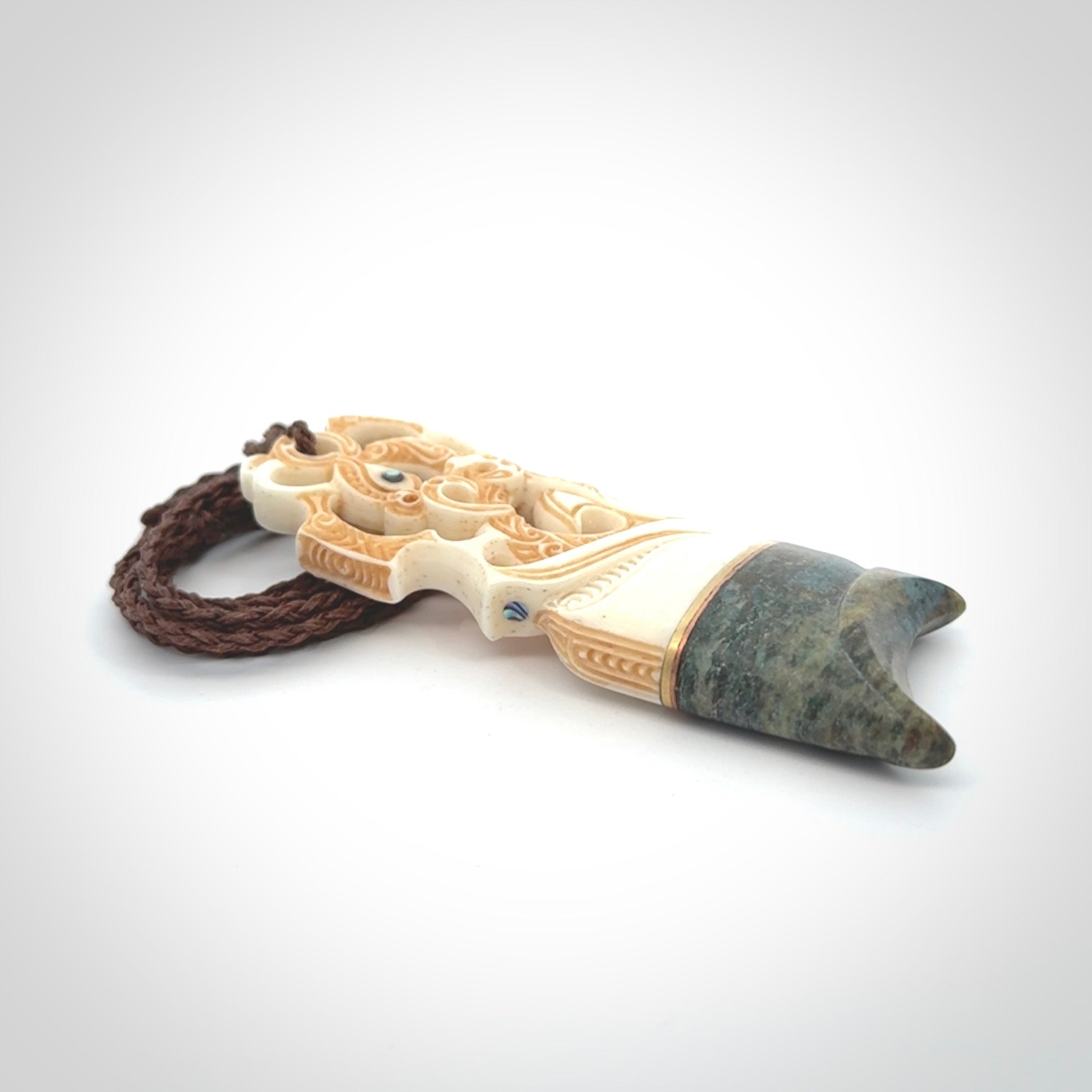 This is a large carved Manaia pendant. It is made from unique materials - New Zealand Obay Stone, Bone, Paua shell, Brass. The face of the Manaia is carved with a traditional design in the front. It is carved front and back and has traditional carved designs. This is a large and very traditional pendant that is a collectors piece.