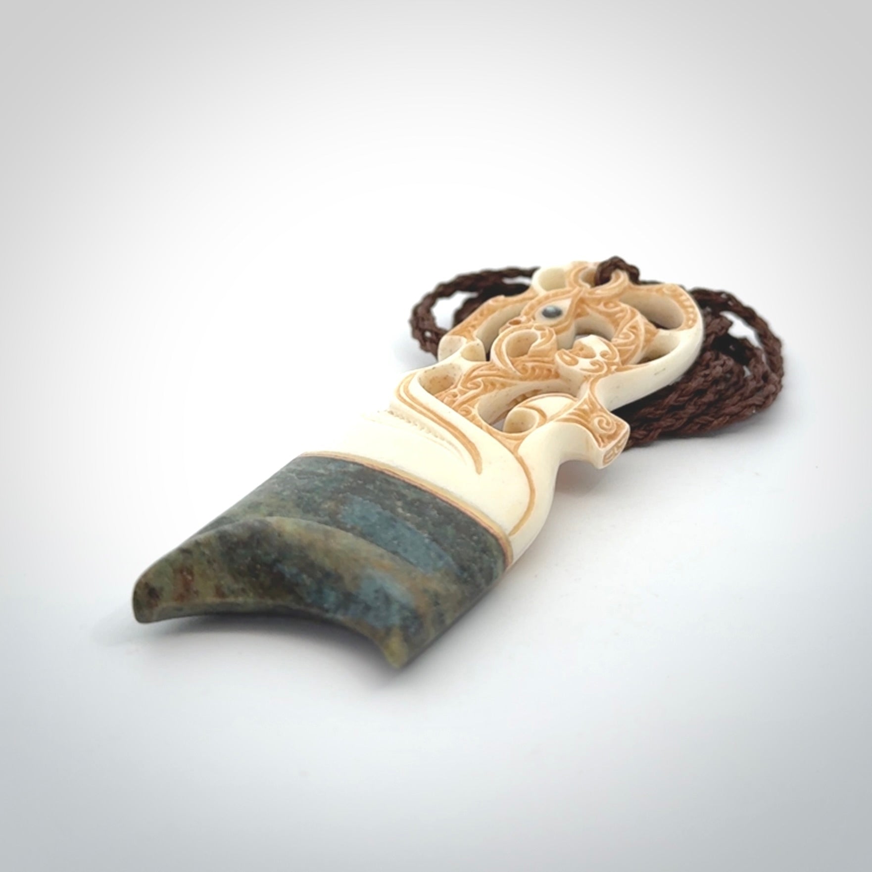 This is a large carved Manaia pendant. It is made from unique materials - New Zealand Obay Stone, Bone, Paua shell, Brass. The face of the Manaia is carved with a traditional design in the front. It is carved front and back and has traditional carved designs. This is a large and very traditional pendant that is a collectors piece.