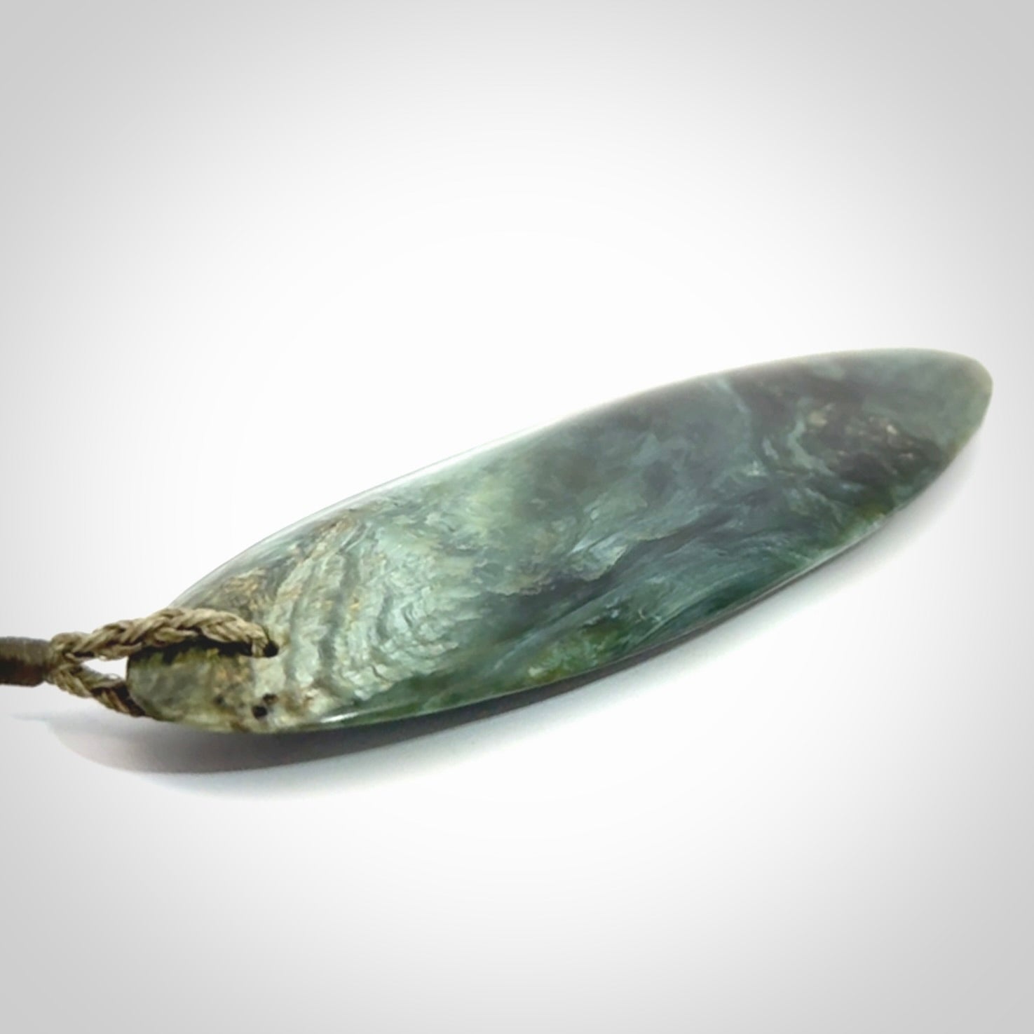 This picture shows a beautiful large sized drop pendant carved in New Zealand Tangiwai pounamu. It is a lovely chatoyant green/blue colour, which is semi-translucent when held to the light. A gorgeous and very meaningful pendant with an adjustable cord.