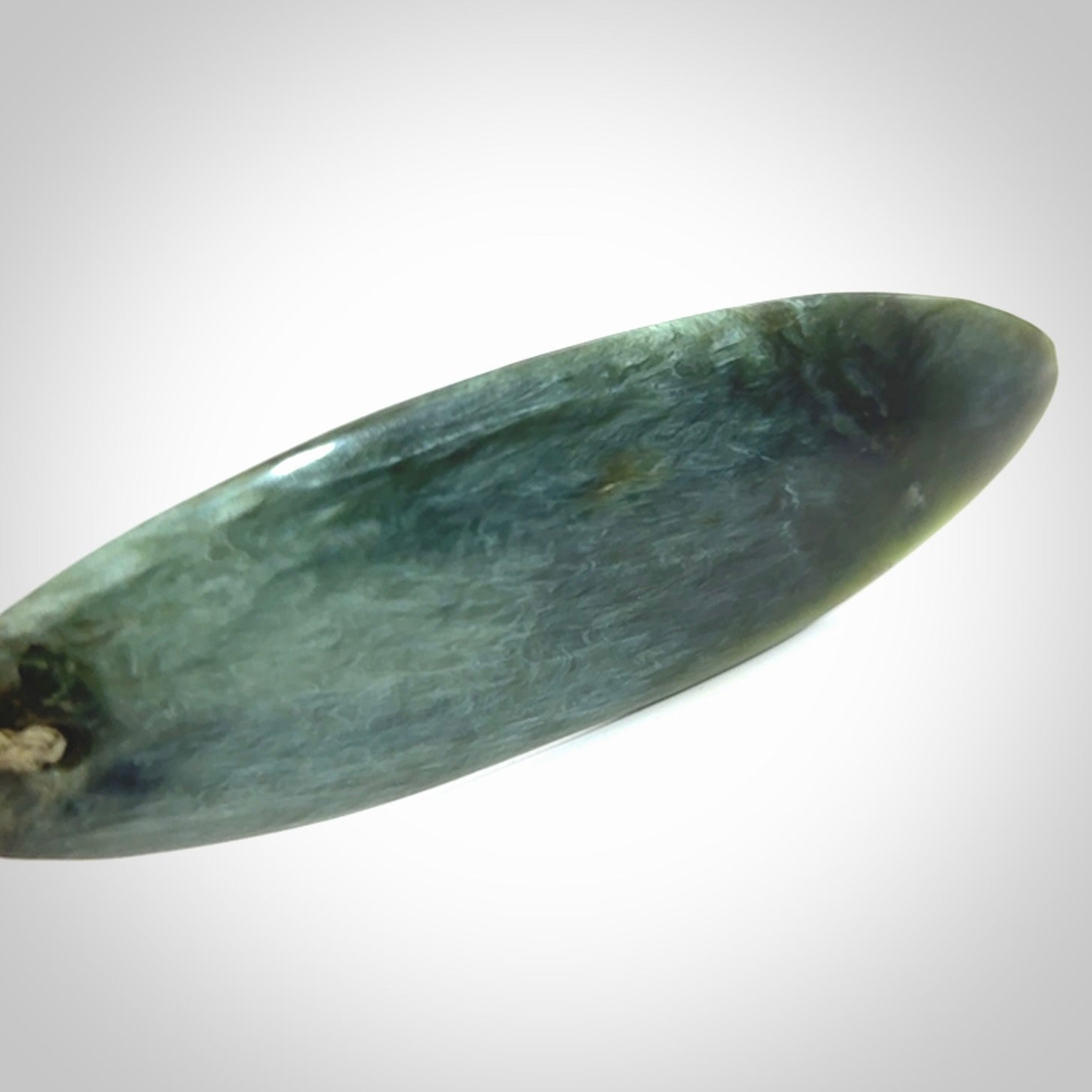 This picture shows a beautiful large sized drop pendant carved in New Zealand Tangiwai pounamu. It is a lovely chatoyant green/blue colour, which is semi-translucent when held to the light. A gorgeous and very meaningful pendant with an adjustable cord.