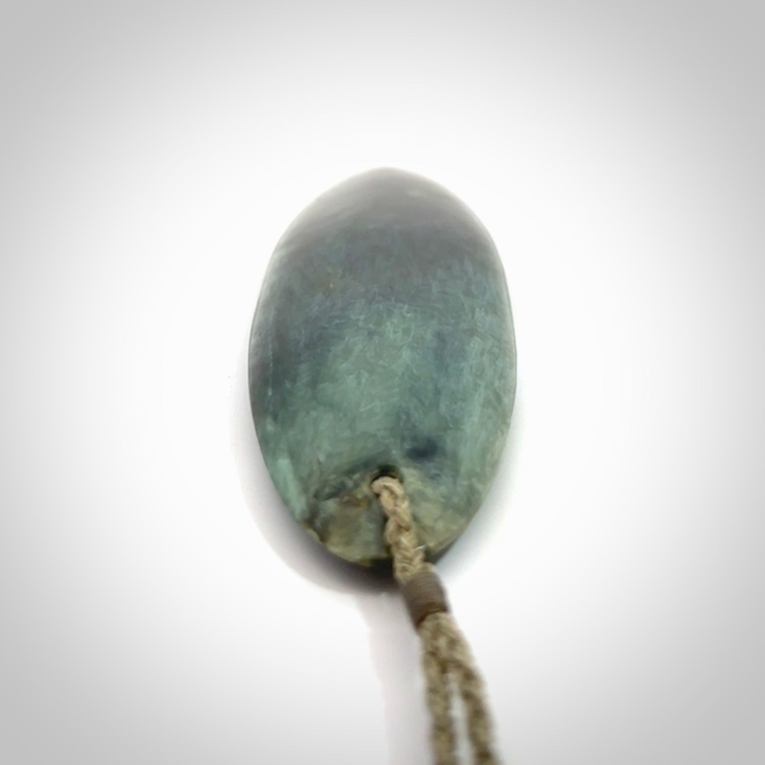 This picture shows a beautiful large sized drop pendant carved in New Zealand Tangiwai pounamu. It is a lovely chatoyant green/blue colour, which is semi-translucent when held to the light. A gorgeous and very meaningful pendant with an adjustable cord.