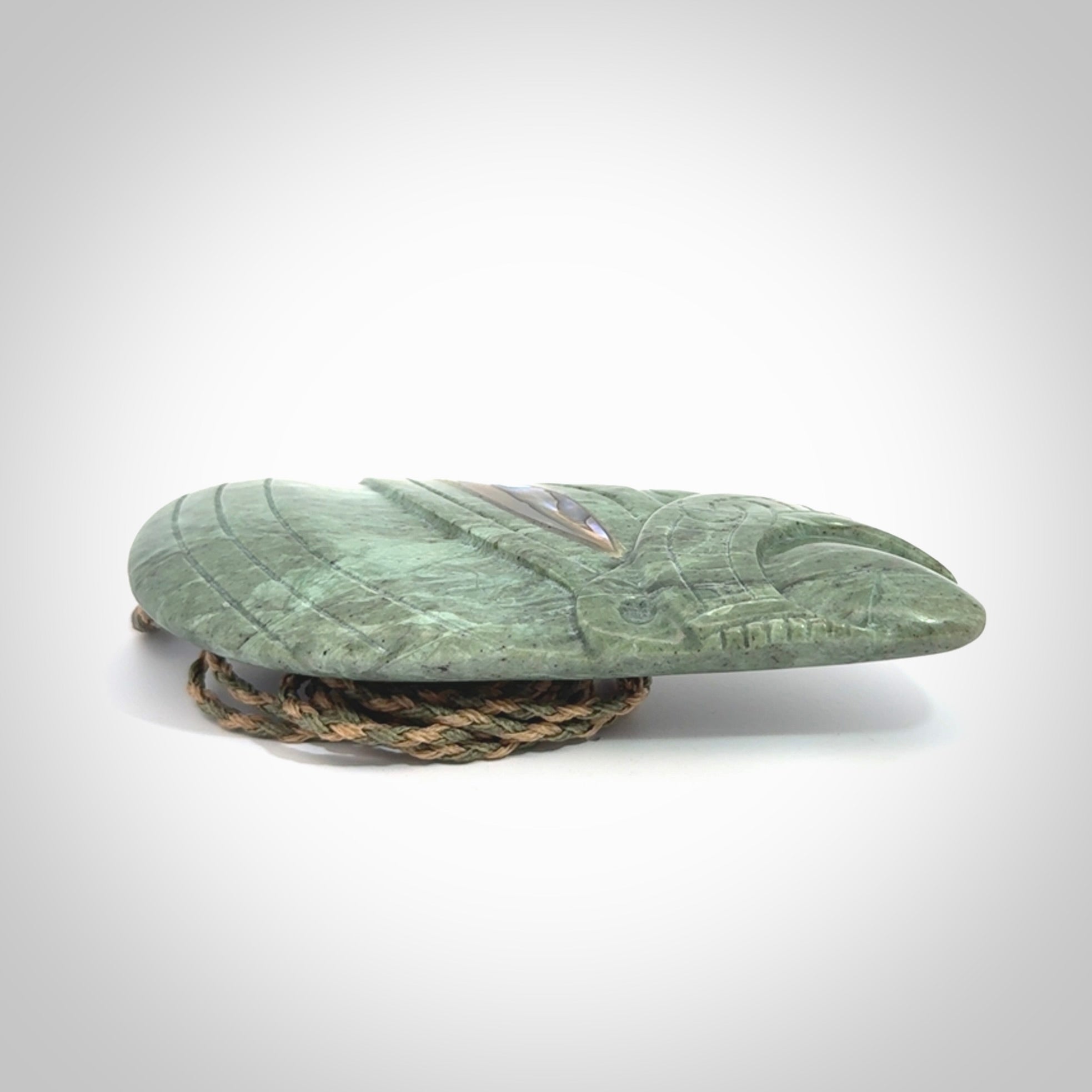 This is a hand carved New Zealand Jade wheku pendant. It is made from New Zealand Jade and Paua shell.