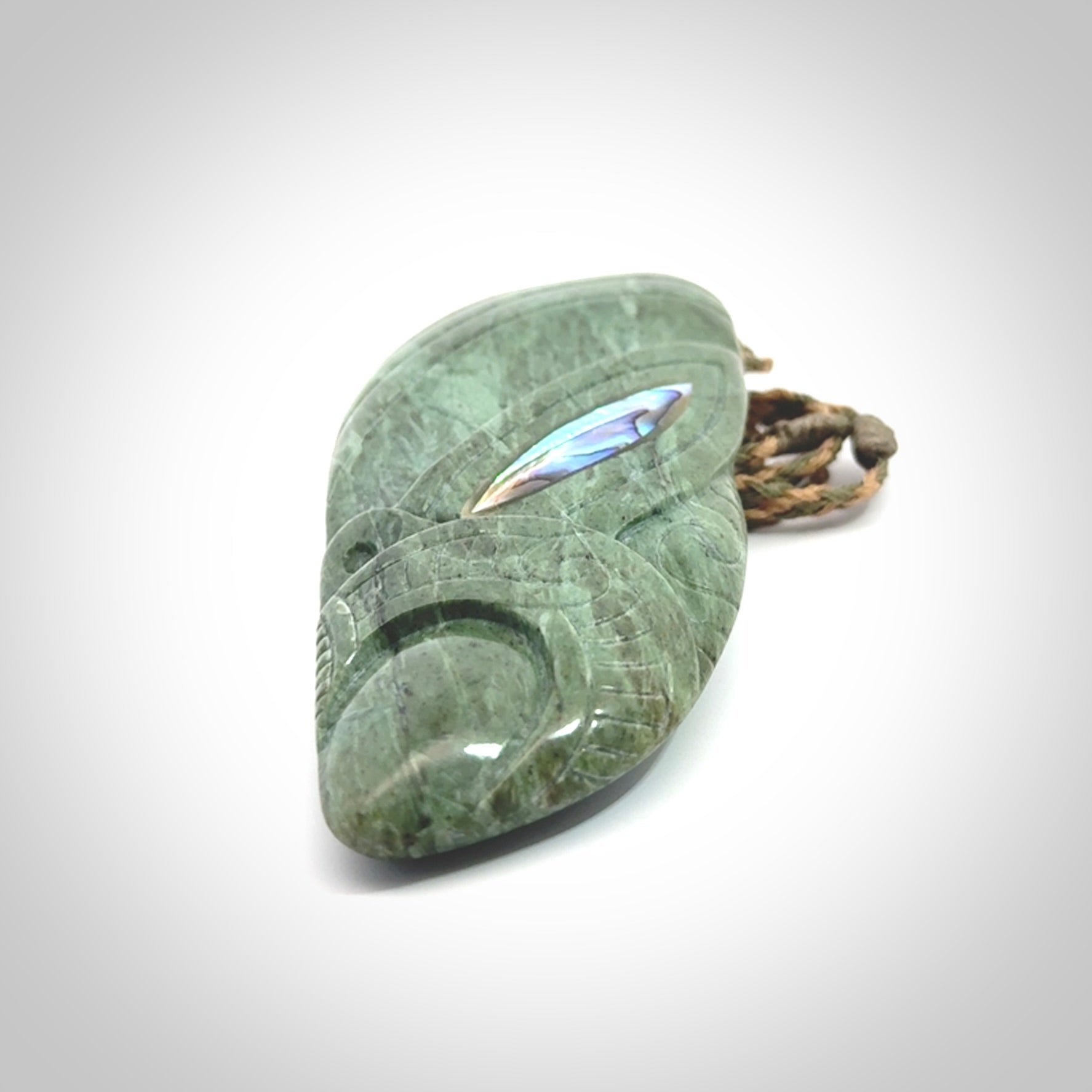 This is a hand carved New Zealand Jade wheku pendant. It is made from New Zealand Jade and Paua shell.