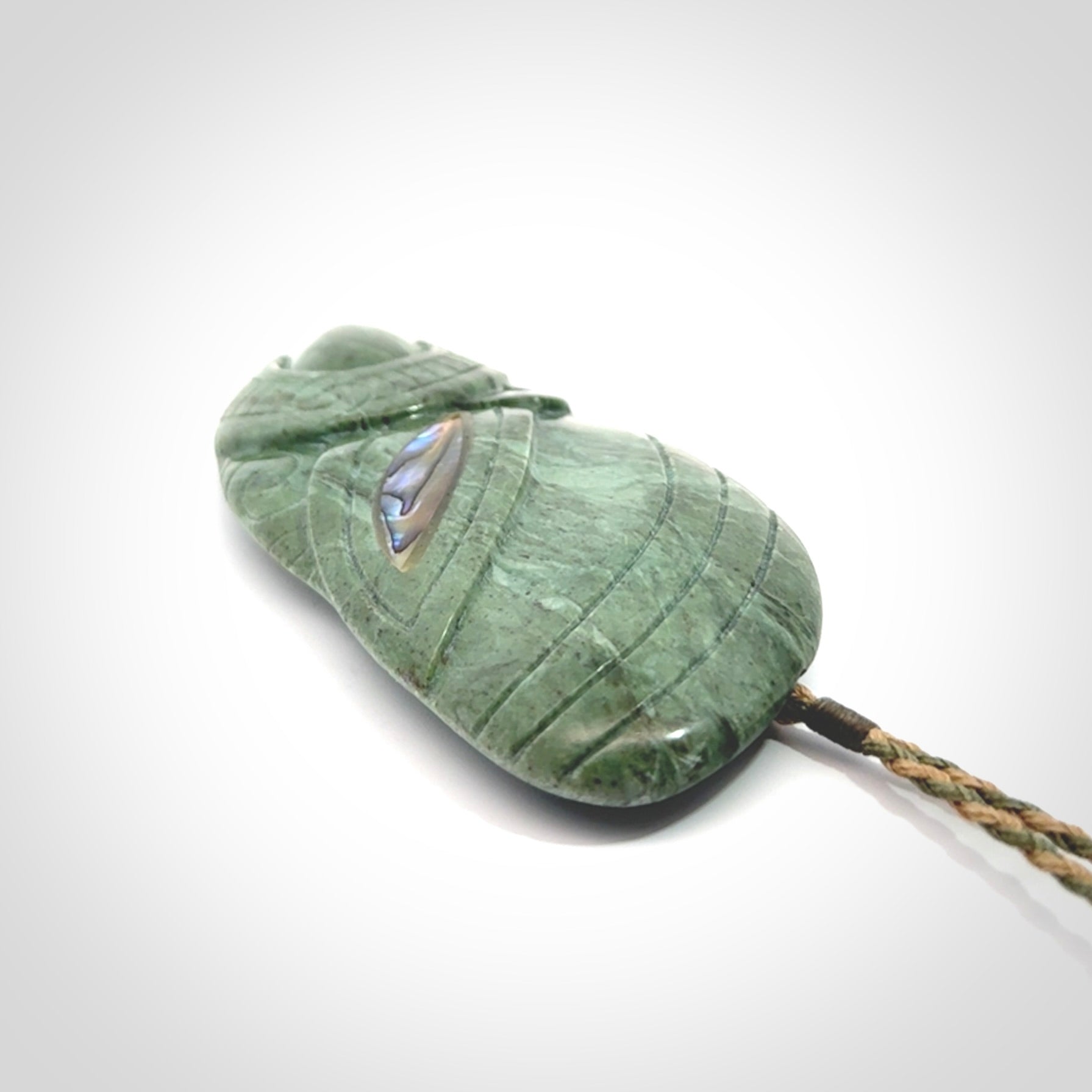 This is a hand carved New Zealand Jade wheku pendant. It is made from New Zealand Jade and Paua shell.