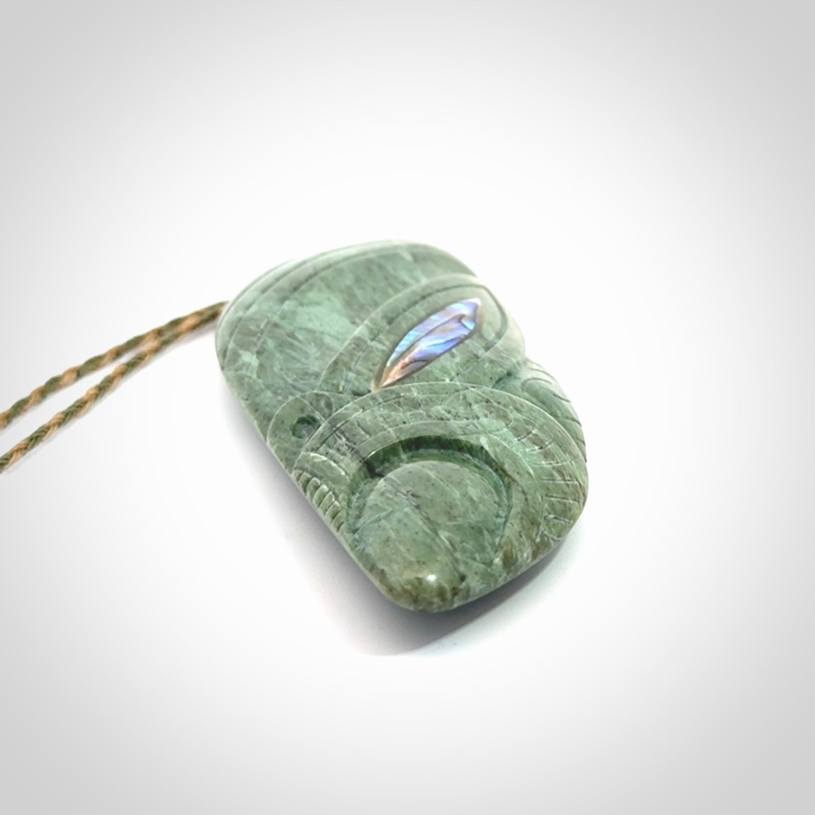 This is a hand carved New Zealand Jade wheku pendant. It is made from New Zealand Jade and Paua shell.