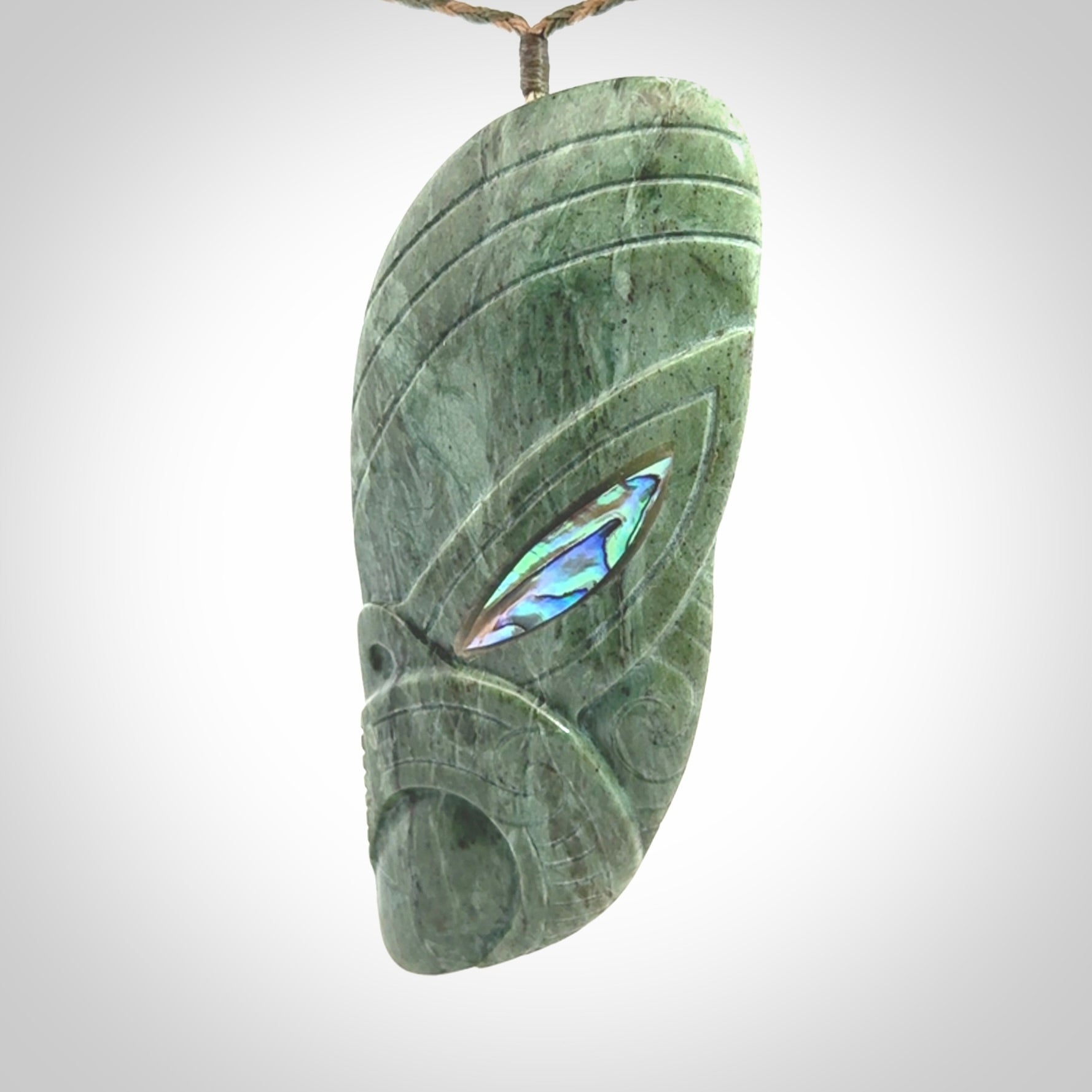 This is a hand carved New Zealand Jade wheku pendant. It is made from New Zealand Jade and Paua shell.