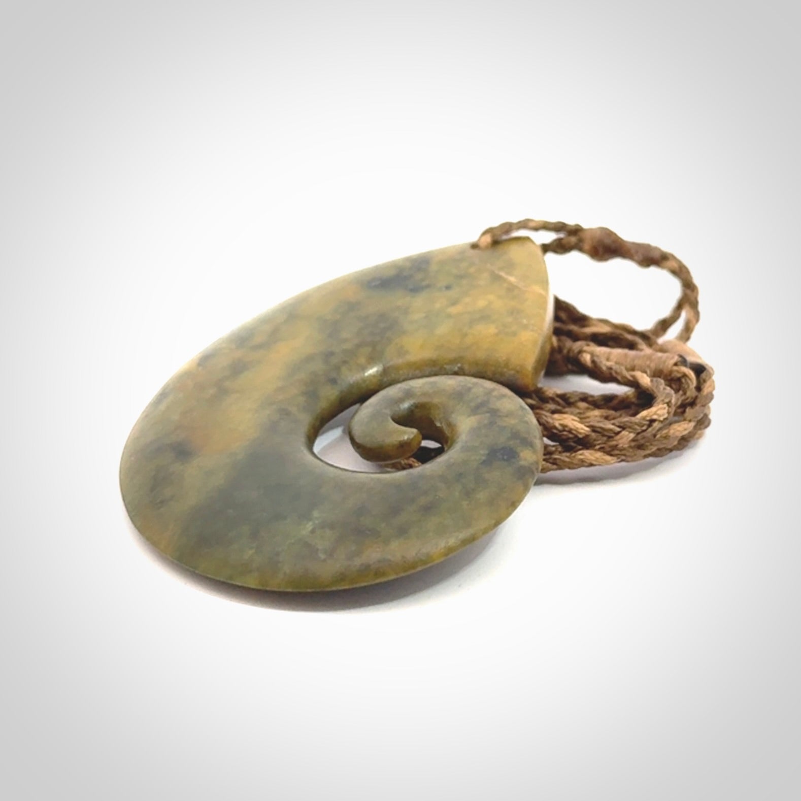 A hand carved koru pendant from New Zealand Flower Jade. The cord is a camel/marrakesh colour and is an adjustable length. A large hand made Koru necklace by New Zealand artist Kerry Thompson.