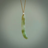 This picture shows a hand carved Spoon River White Jade drop pendant with adjustable cord. The jade is a very light, white green with a shimmer of darker tones in the stone. It is suspended from a tan coloured cord. Delivery is free worldwide.