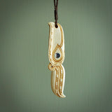 This picture shows a carved hawk in bone. It is a drop shaped pendant. The artist has carved traditional decorative kowhaiwhai designs into the body and these run up the sides of the hawk. These have specific meanings. It is provided with a hand-plaited brown cord that is length adjustable. Shipping is included and we ship worldwide.