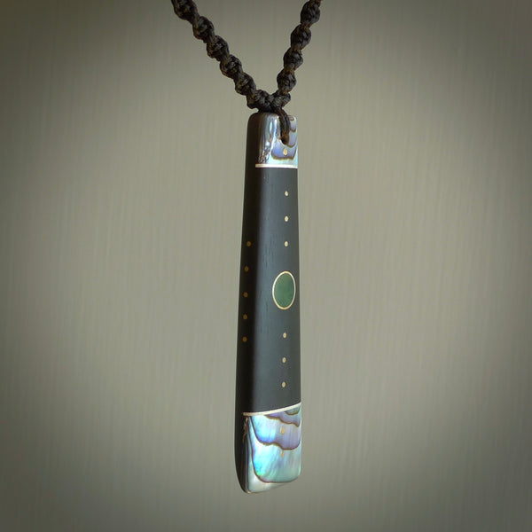 This photo shows a medium sized Toki pendant hand carved from antique elephant statue with New Zealand Pounamu, Green Stone, and Paua Shell inlay alongside; brass and silver. This is a stand out one off necklace for those who appreciate art to wear. It is provided with a cord in black that is a fixed length with Paua Shell Toggle. We ship this piece worldwide and shipping is included in the price.