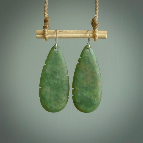 This picture shows New Zealand Pounamu, jade feather earrings with sterling silver hooks. Hand made unique and contemporary feather earrings by Kerry Thompson. Hand carved here in New Zealand from New Zealand Jade. One pair only.