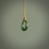 This piece is a oval round, ring pendant. It was carved for us by Ric Moor from a lovely light and milky green piece of New Zealand jade. It is suspended on a beige coloured braided cord that is length adjustable.