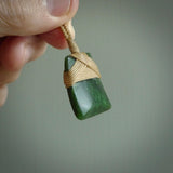 Hand carved from a lovely piece of local New Zealand Jade. The quality of the workmanship and design is outstanding - this is a piece you will want to wear all the time. We have suspended this from a 3-plait tan cord which can be adjusted with a couple of slip knots and tan binding.