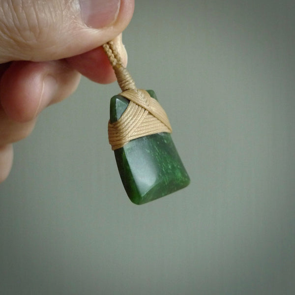Hand carved from a lovely piece of local New Zealand Jade. The quality of the workmanship and design is outstanding - this is a piece you will want to wear all the time. We have suspended this from a 3-plait tan cord which can be adjusted with a couple of slip knots and tan binding.