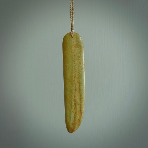 Raukaraka Pounamu drop pendant. Hand carved by Rhys Hall for NZ Pacific. Handmade jewellery for sale online. The cord is a 4-braid plait in tan and has a loop and pebble toggle closure. Drop necklace for men and women. Scandinesian Toki necklace hand made from New Zealand Jade.